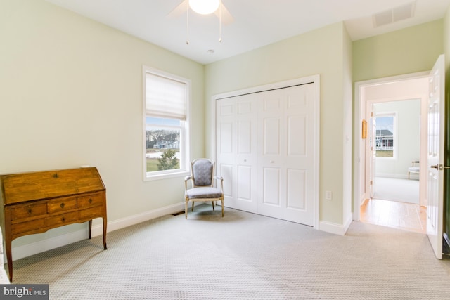 living area with light carpet and ceiling fan