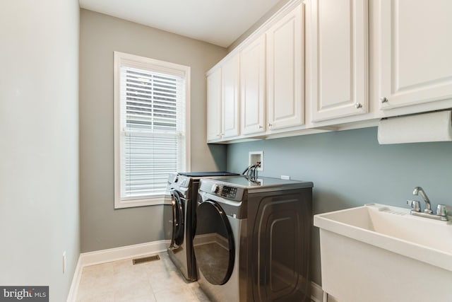 washroom with cabinets, independent washer and dryer, light tile patterned floors, and sink