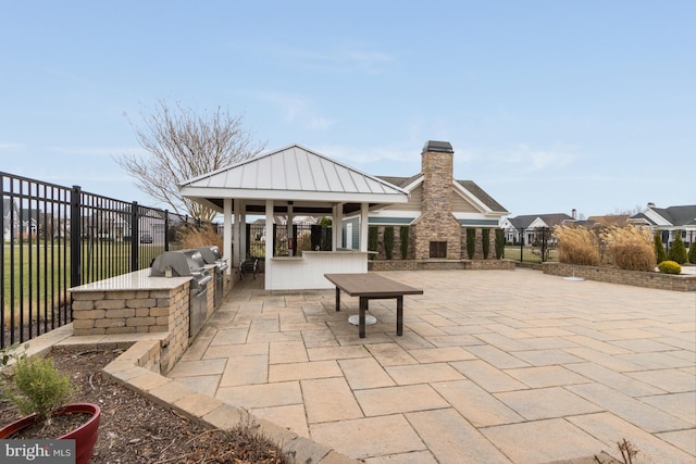 view of patio / terrace featuring a bar and an outdoor kitchen