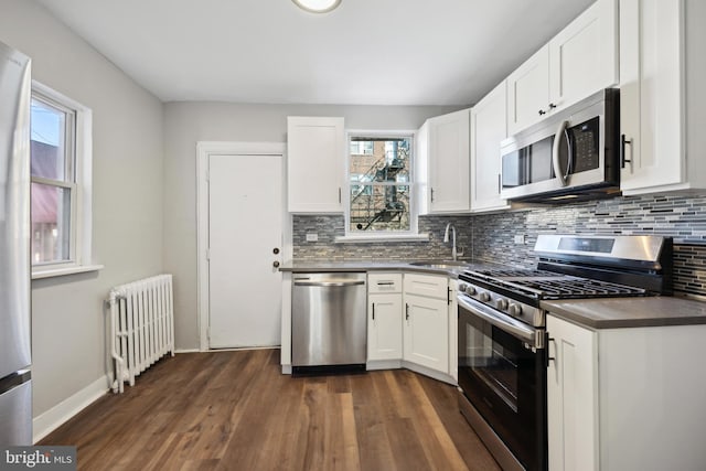 kitchen featuring white cabinetry, sink, radiator heating unit, and stainless steel appliances