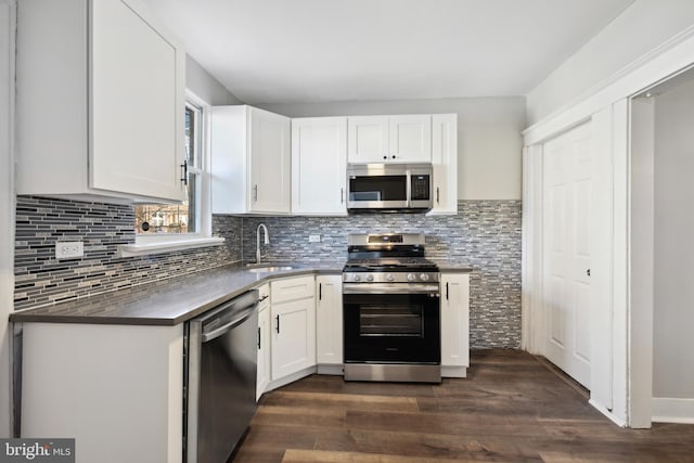 kitchen with white cabinets, appliances with stainless steel finishes, dark hardwood / wood-style floors, and sink