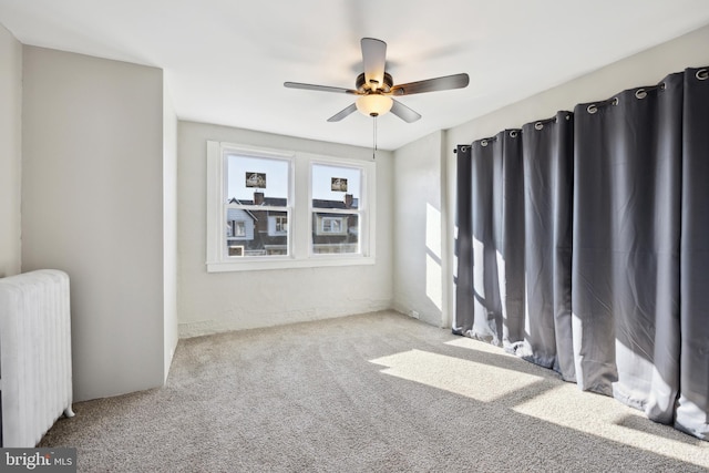 spare room with carpet, radiator, and ceiling fan