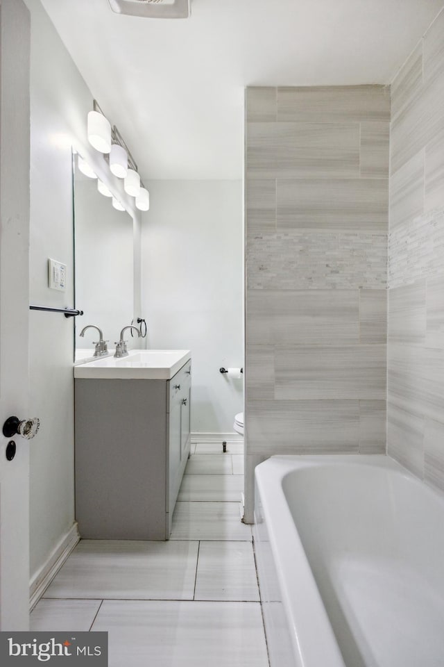 bathroom featuring tile patterned flooring, vanity, toilet, and a tub