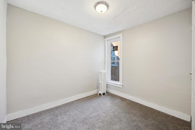 spare room featuring carpet, radiator heating unit, and a textured ceiling