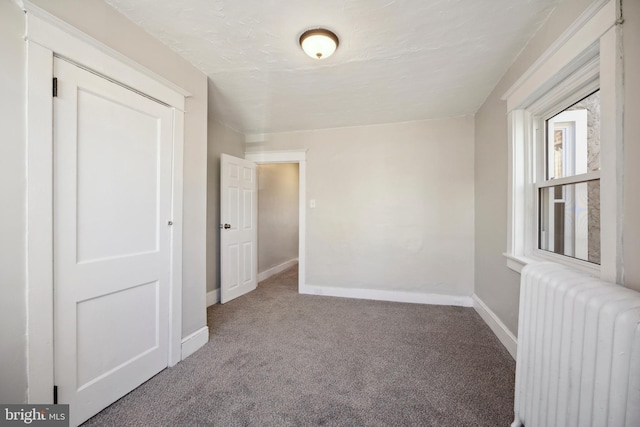 empty room featuring radiator heating unit and carpet floors