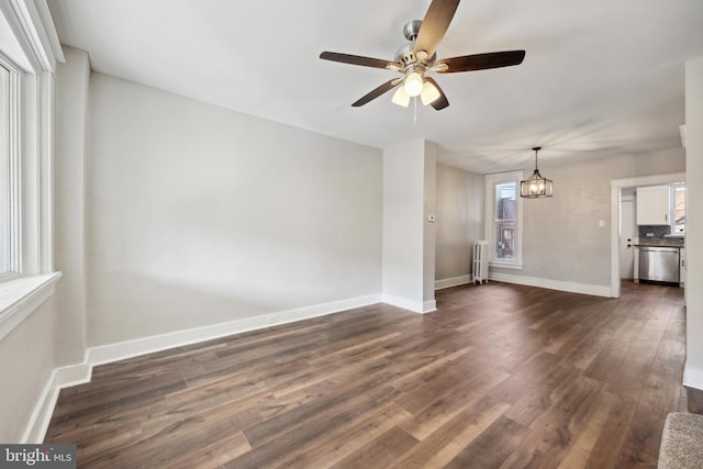 unfurnished living room featuring radiator, dark wood-type flooring, and ceiling fan with notable chandelier