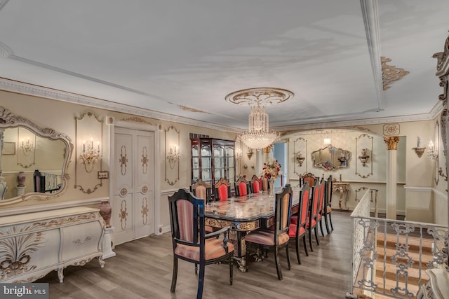 dining area with wood-type flooring, crown molding, and a chandelier