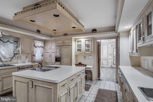 kitchen with paneled fridge, black electric cooktop, a raised ceiling, crown molding, and a center island