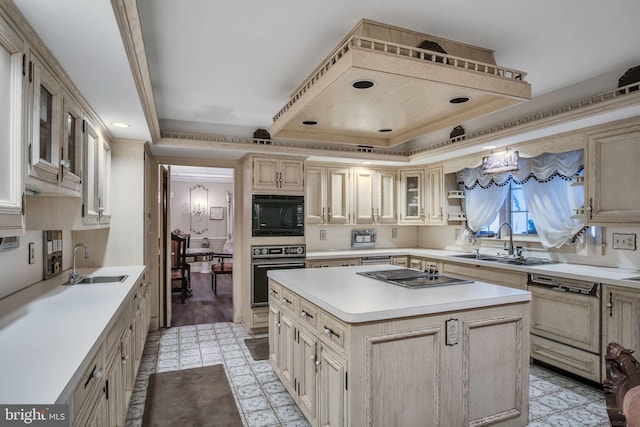 kitchen with cream cabinets, a center island, black appliances, and sink