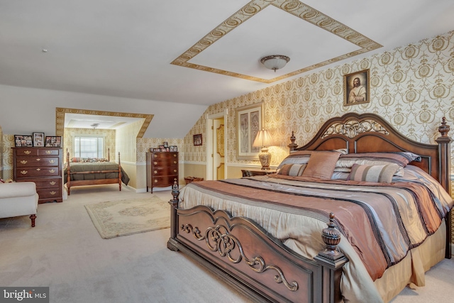 bedroom with vaulted ceiling, light colored carpet, and ensuite bath