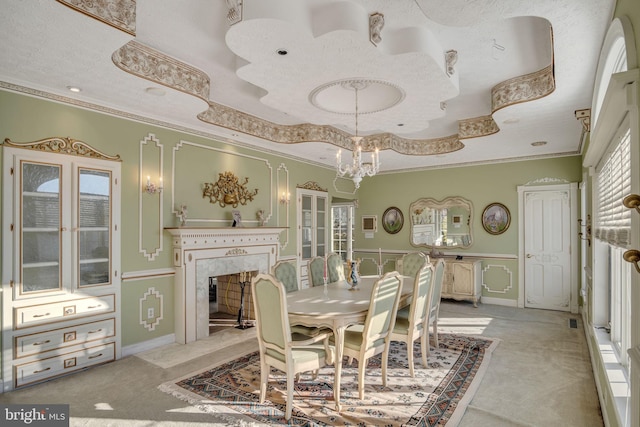 carpeted dining room featuring a notable chandelier, ornamental molding, a fireplace, and a tray ceiling