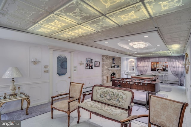 interior space featuring a tray ceiling, a brick fireplace, baseboard heating, and billiards