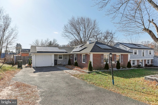 view of front of house with solar panels, a garage, and a front lawn