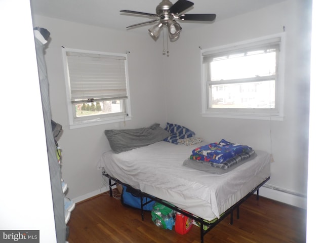 bedroom featuring ceiling fan, dark hardwood / wood-style flooring, and a baseboard heating unit