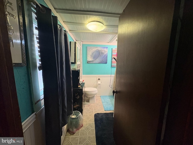 bathroom with toilet and wood walls