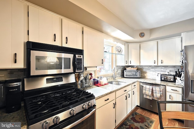 kitchen featuring stainless steel appliances, white cabinetry, and sink