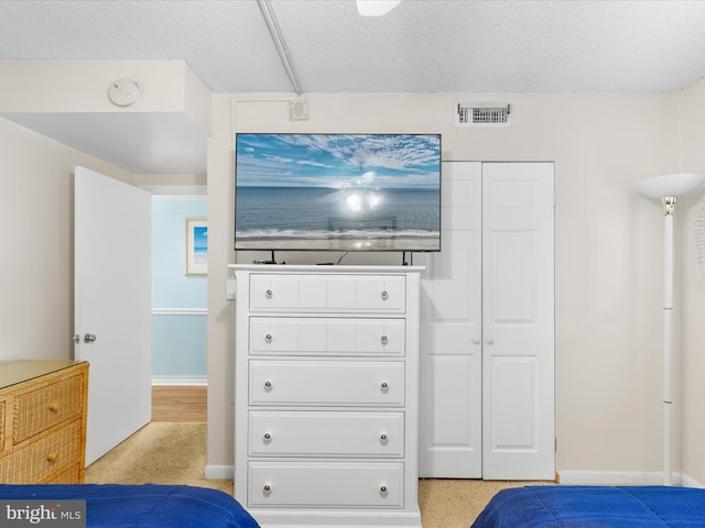 bedroom with light carpet and a textured ceiling