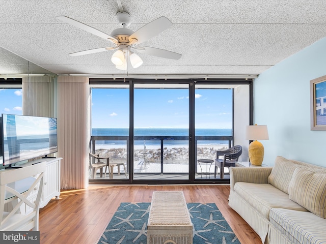 living room with hardwood / wood-style flooring, ceiling fan, floor to ceiling windows, and a water view