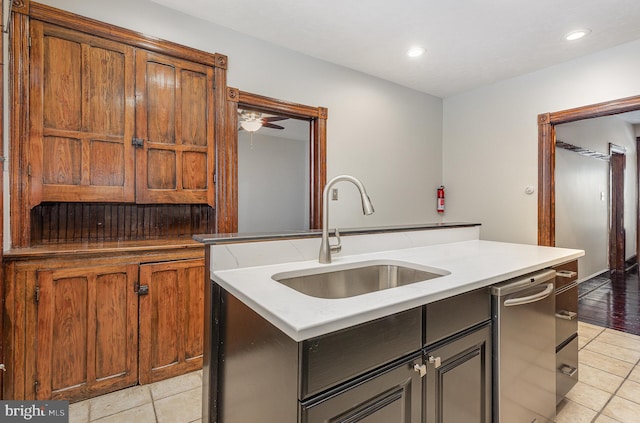 kitchen with light tile patterned floors, a center island with sink, ceiling fan, and sink