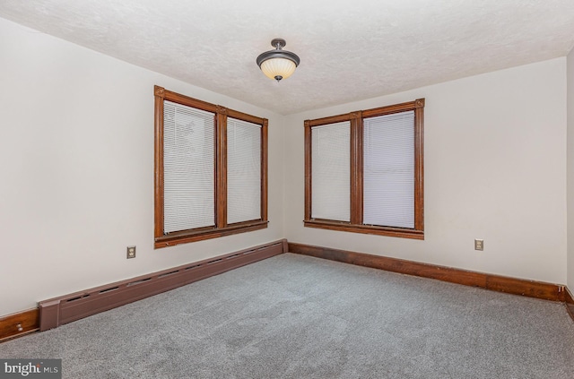 spare room with carpet, a textured ceiling, and a baseboard radiator