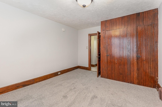 unfurnished bedroom featuring light carpet, a closet, and a textured ceiling