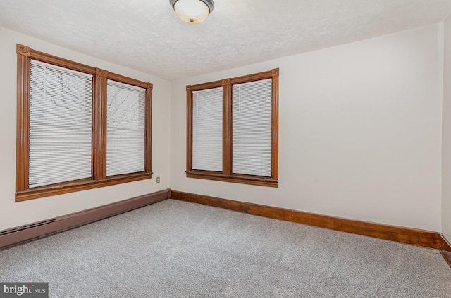 empty room with carpet, a textured ceiling, and a baseboard heating unit