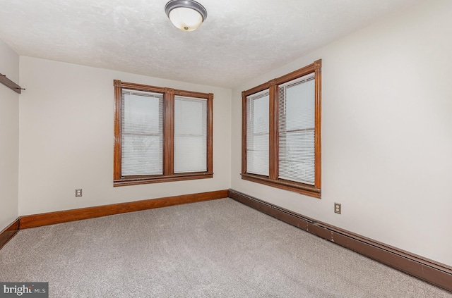 carpeted empty room with a textured ceiling and baseboard heating