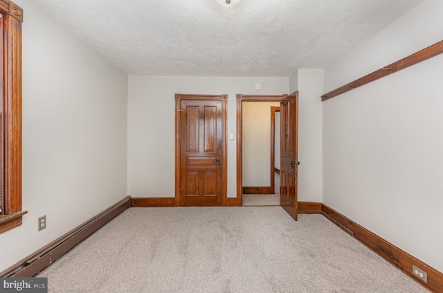 unfurnished bedroom with light colored carpet, a textured ceiling, and a baseboard radiator