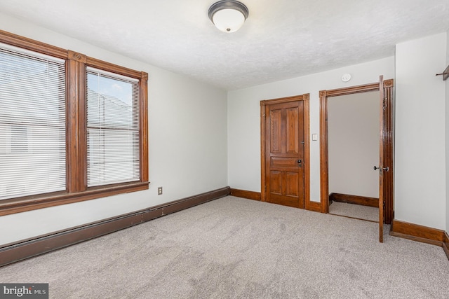 unfurnished bedroom featuring light carpet and a baseboard heating unit