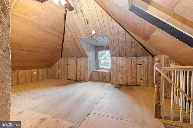 additional living space with vaulted ceiling, ceiling fan, and wooden walls