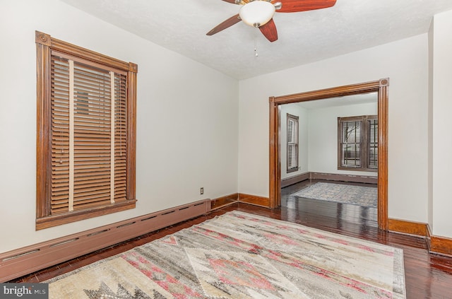 unfurnished room featuring hardwood / wood-style flooring, ceiling fan, and baseboard heating