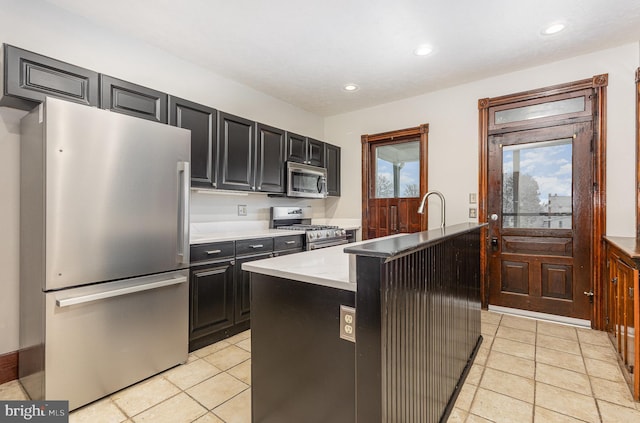 kitchen featuring light tile patterned floors, stainless steel appliances, and an island with sink