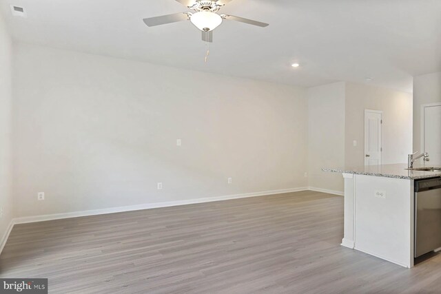 interior space featuring sink, stainless steel dishwasher, ceiling fan, light wood-type flooring, and light stone counters