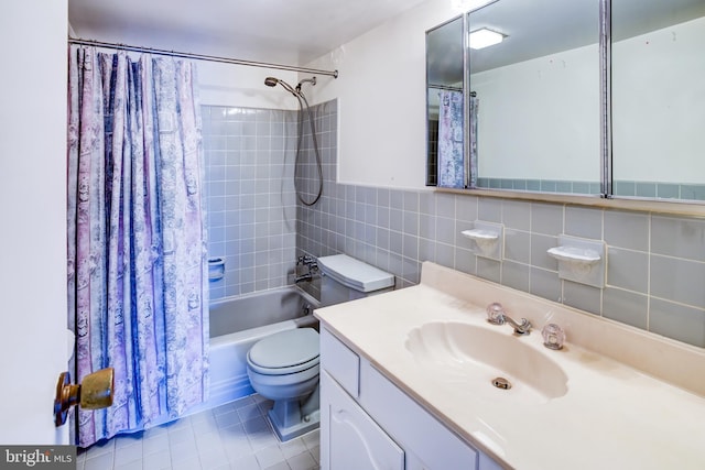 full bathroom with shower / bathtub combination with curtain, tile patterned flooring, tile walls, vanity, and toilet