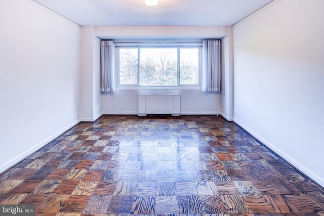 empty room with radiator heating unit and dark parquet floors