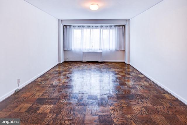 spare room with radiator heating unit and dark parquet flooring