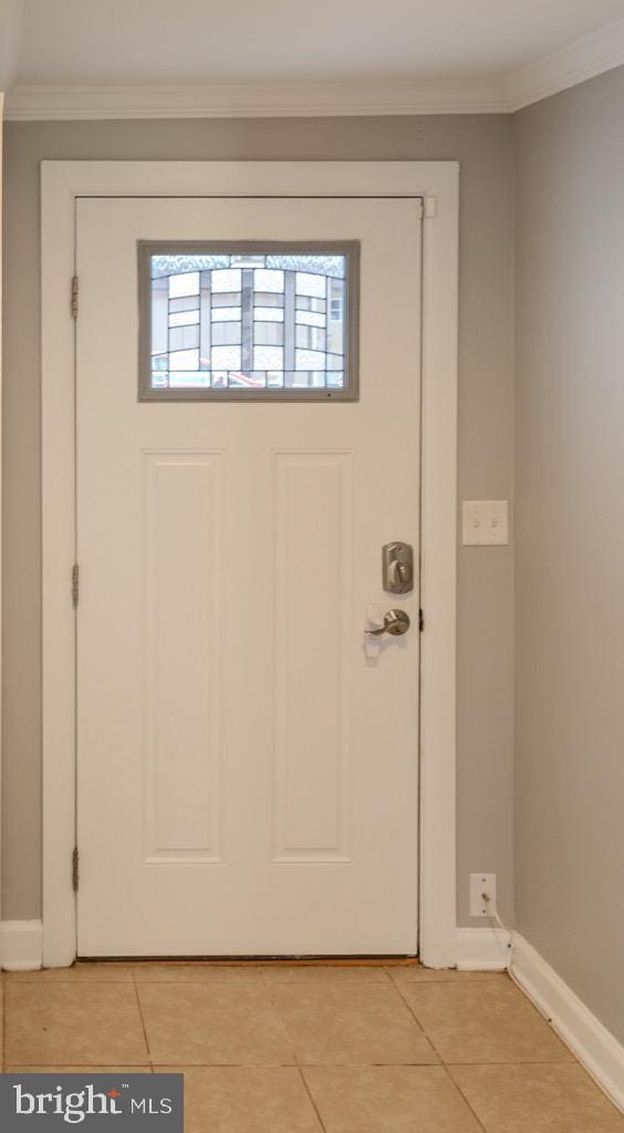 entryway with crown molding and light tile patterned flooring