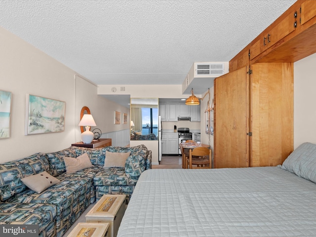 bedroom with a textured ceiling, stainless steel refrigerator, and a closet