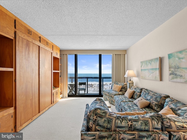 living room featuring a textured ceiling, a water view, floor to ceiling windows, and carpet floors