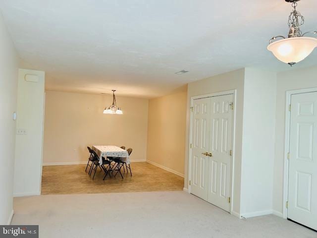 dining area with light colored carpet and a notable chandelier