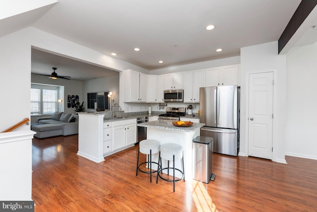 kitchen with white cabinetry, light stone countertops, kitchen peninsula, and appliances with stainless steel finishes