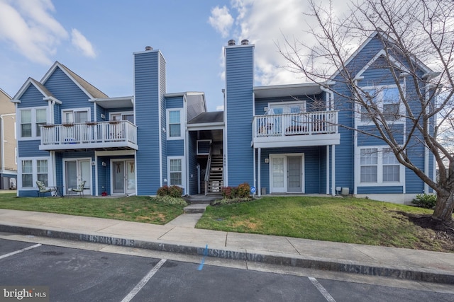 multi unit property with a balcony and a front lawn