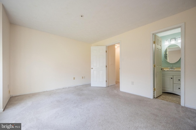 unfurnished bedroom featuring connected bathroom, sink, and light colored carpet