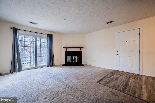 unfurnished living room with carpet and a textured ceiling