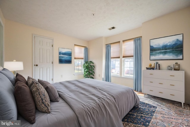 carpeted bedroom featuring a textured ceiling and multiple windows