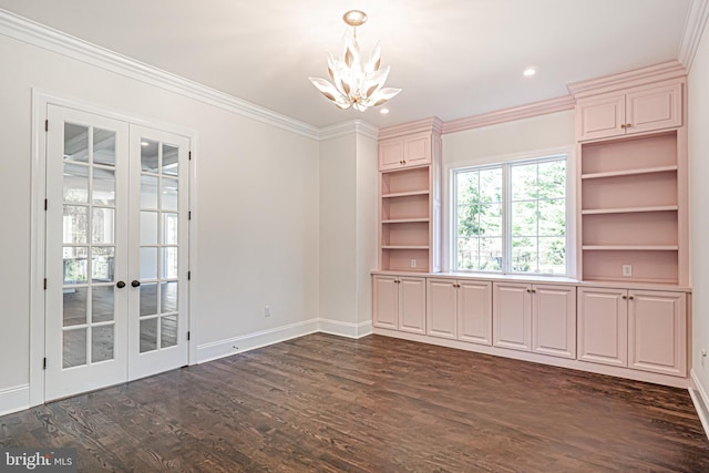 empty room with dark hardwood / wood-style floors, crown molding, a chandelier, and french doors