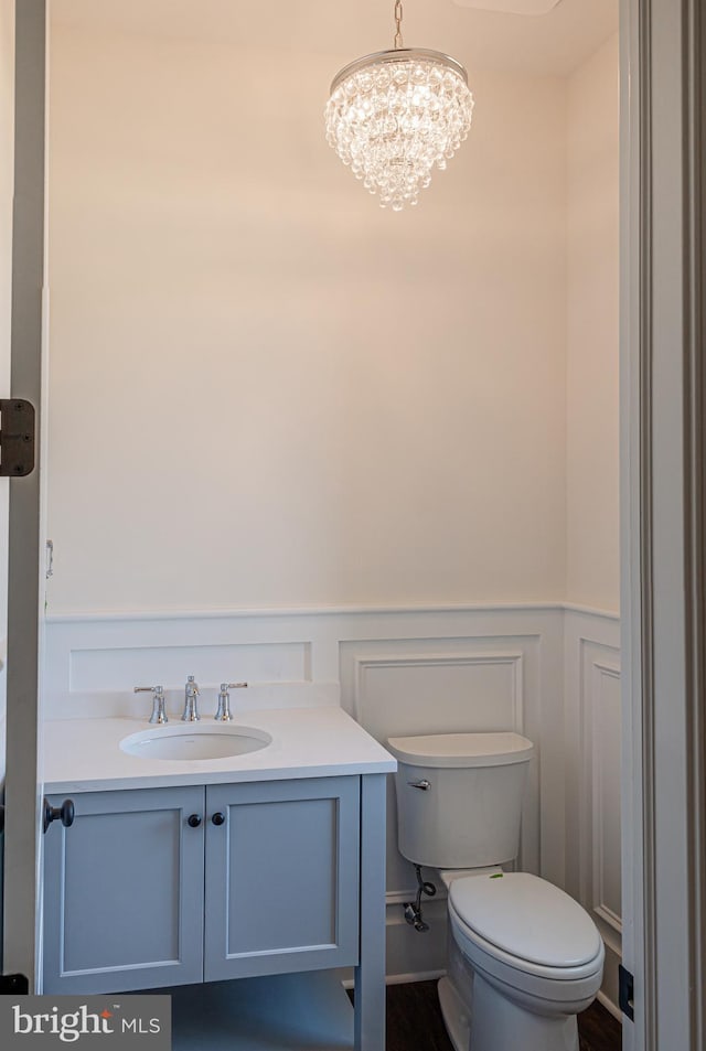 bathroom featuring a notable chandelier, toilet, and vanity