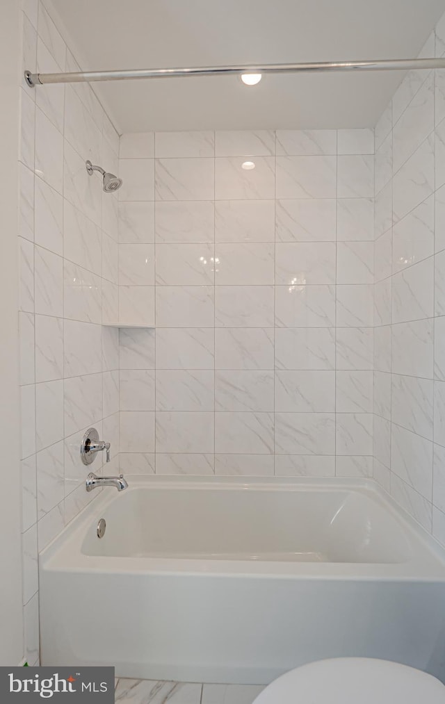 bathroom featuring tiled shower / bath combo and toilet