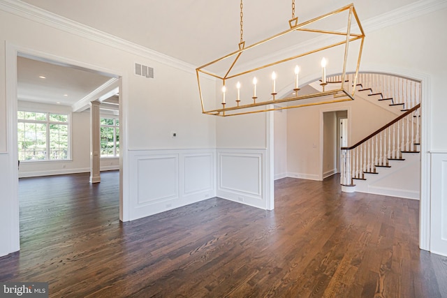 unfurnished dining area with dark hardwood / wood-style floors, decorative columns, ornamental molding, and an inviting chandelier