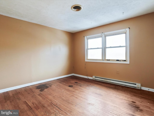 spare room featuring a textured ceiling, a baseboard radiator, and hardwood / wood-style flooring